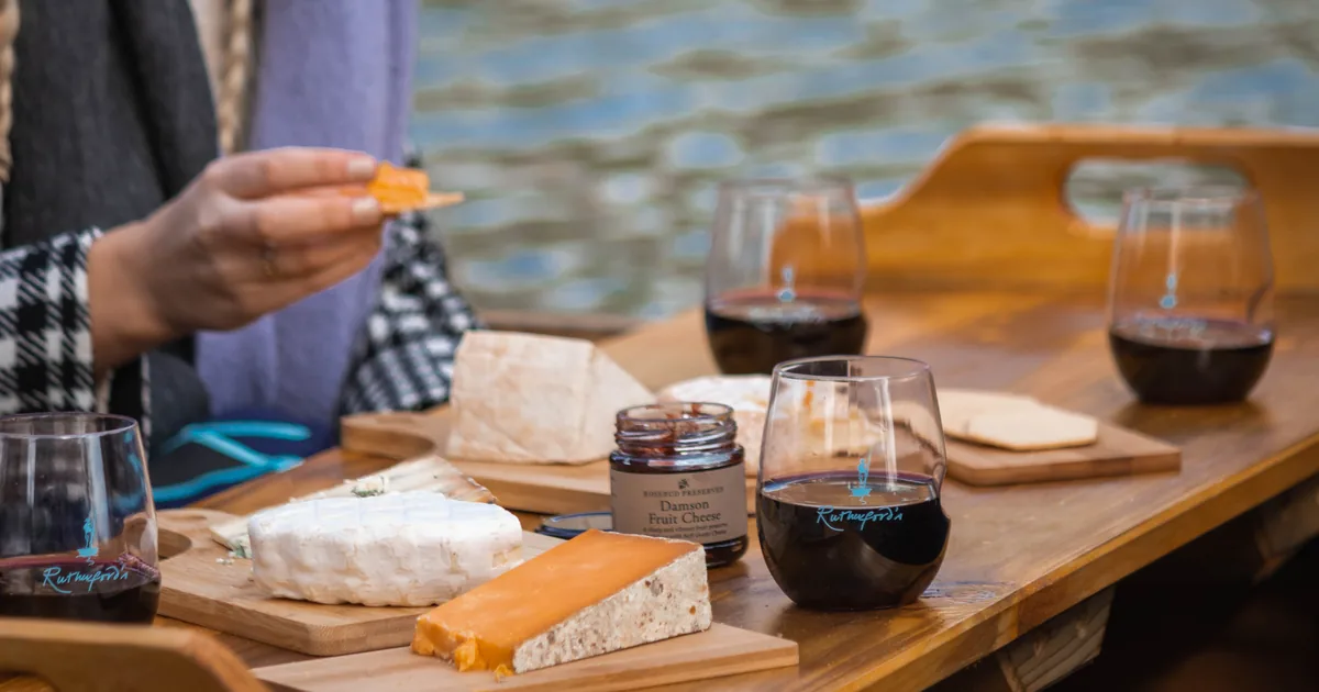 A wooden table with cheese and red wine on a private punt on the River Cam